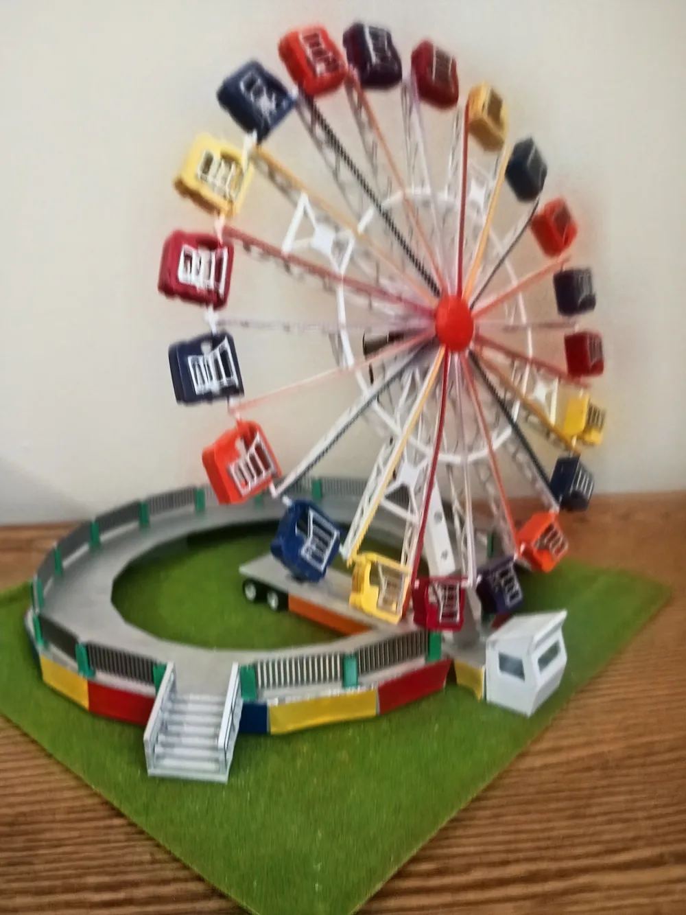 Handmade HO scale model Ferris wheel with colorful gondolas on a green base
